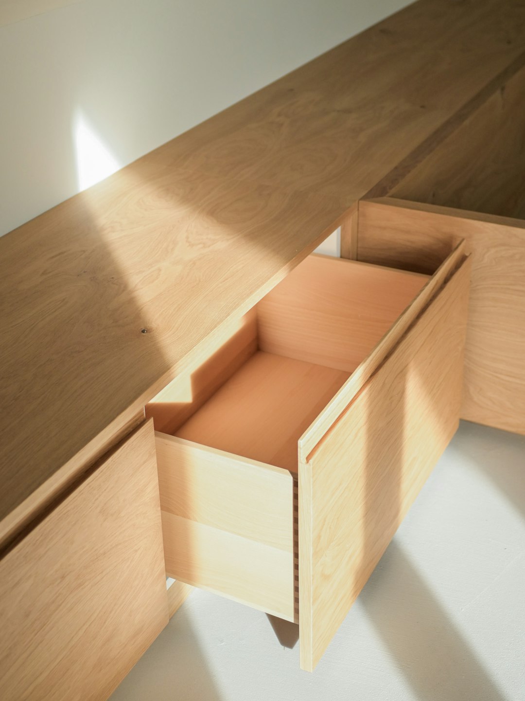 light-streams-across-wooden-cabinets-with-an-open-drawer-jhm5hjjxx1e